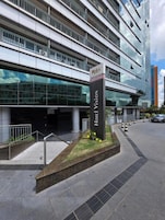 Un hotel moderno con fachada de vidrio, un letrero llamativo que dice 'Hotel Vision', y un área ajardinada con un pequeño jardín.