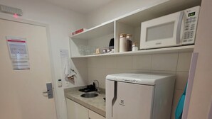 Cocina compacta con microondas, refrigerador y lavamanos.