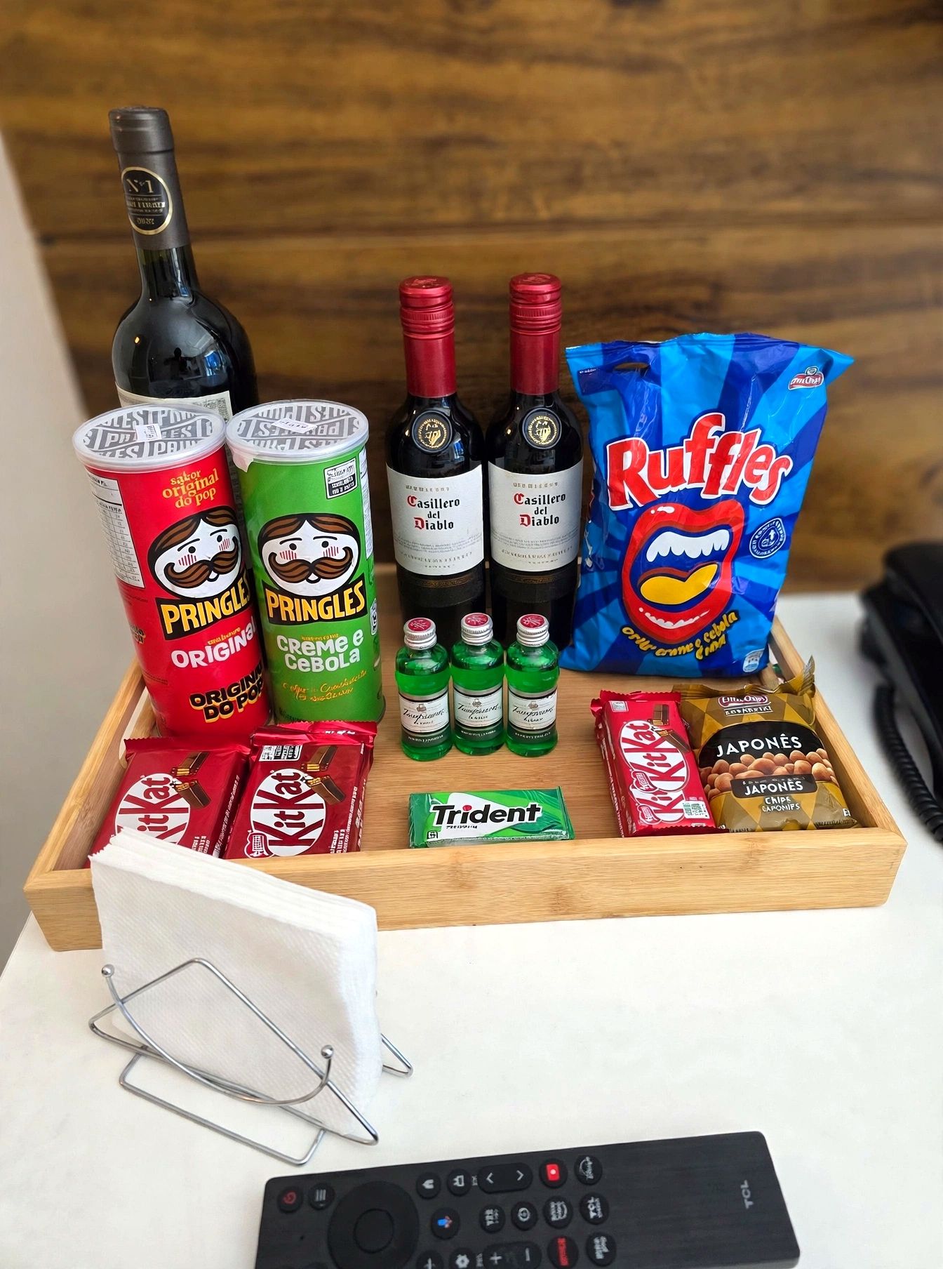 Ein Tablett mit Snacks, Getränken und einer Fernbedienung.