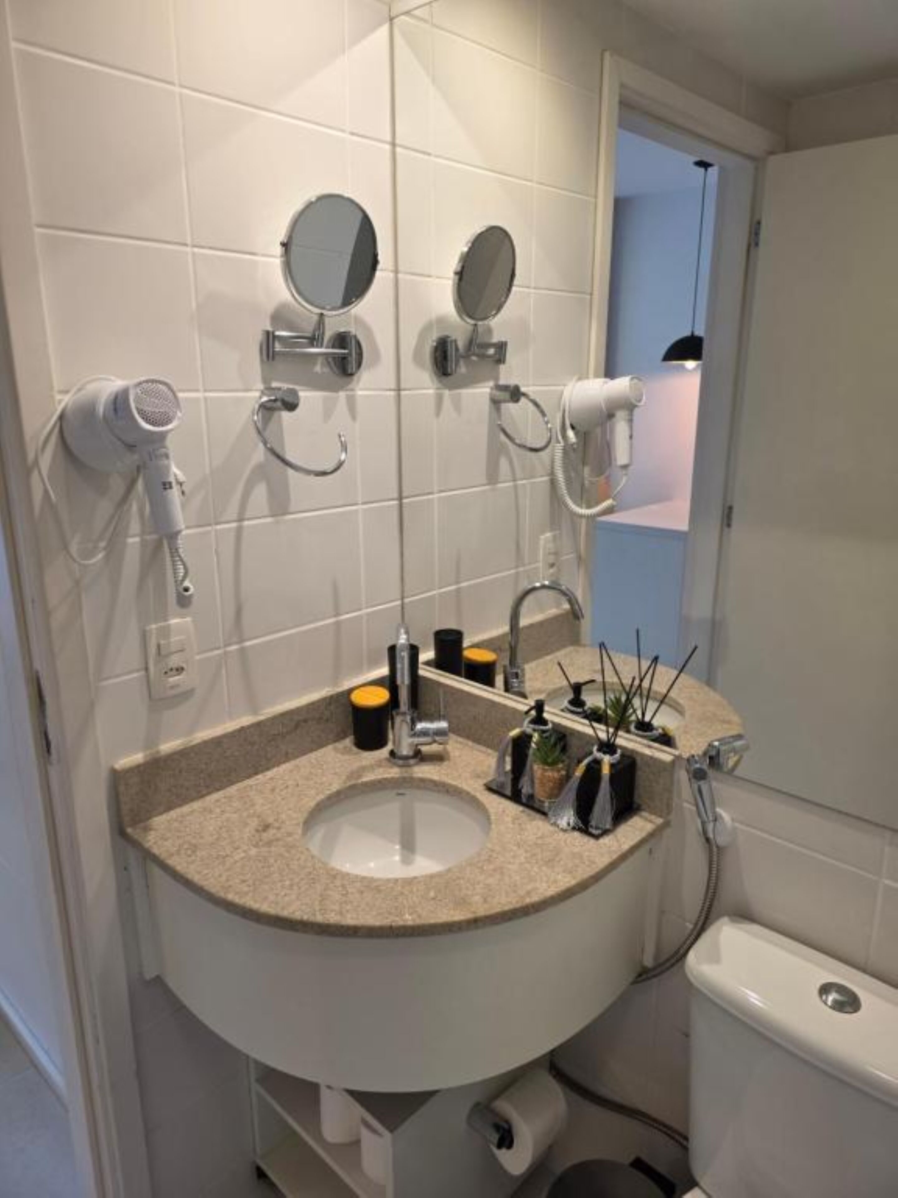 Un baño con lavamanos, espejos, secador de pelo y un inodoro.