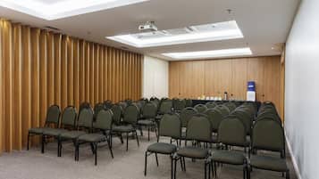 A conference room with rows of chairs, a projector, and a wooden panel wall.