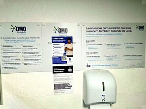 Eine Wand mit Informationspostern zur Wäschepflege und einem Papierhandtuchspender.