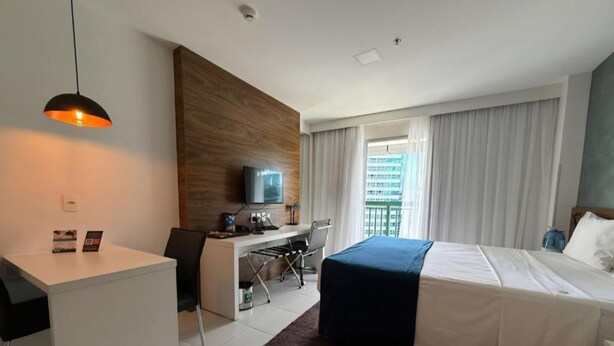 Una habitación de hotel con cama, escritorio, silla, televisor y vistas a la ciudad.