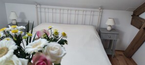 A bedroom with a white bed, two bedside tables with lamps, a wooden headboard, and a floral arrangement on the left. - Pivoine **** Vacation Rental for 6 People with a Spa and Pool (Bournazel)