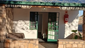 Entrada de um prédio com uma placa indicando 'ONSEEPKANS' e um portão verde.