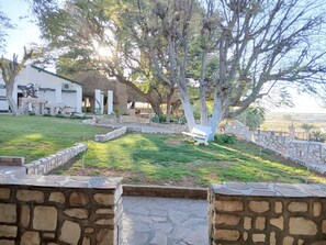 A courtyard with stone walls, a grassy area, and a white building with columns.