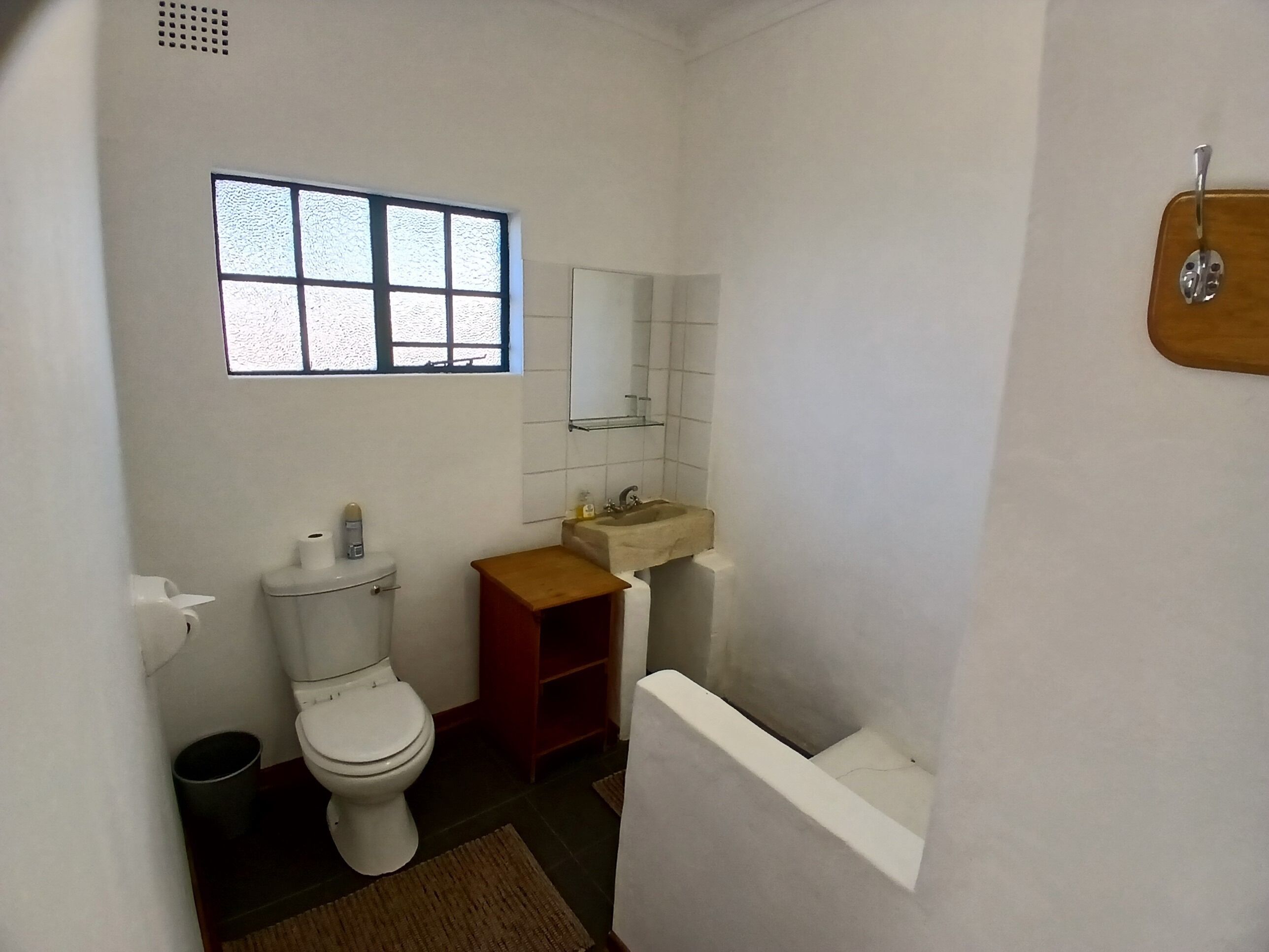 A small, compact bathroom with a toilet, sink, and window.