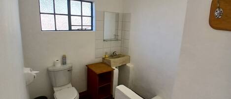 A small, compact bathroom with a toilet, sink, and window.