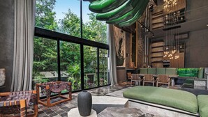 A modern interior with a large window, a green hanging light fixture, and a seating area with a green sofa and wooden chairs. - Rooftop Pool, Spa! Luxury 4BR Designer Tulum Villa (Tulum)