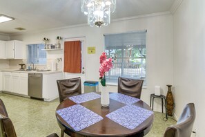 A dining area with a round table, chairs, a vase with flowers, and a kitchen in the background. - Inviting Unit, 10 Mi to Airport & Vintage Park! (Houston)