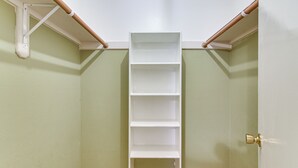 A room with a white shelving unit against a green wall, a door with a brass handle, and wooden beams on the ceiling. - Inviting Unit, 10 Mi to Airport & Vintage Park! (Houston)