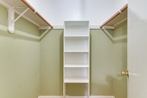 Ein Zimmer mit einer weißen Regaleinrichtung an einer grünen Wand, einer Tür mit Messingklinke und Holzbalken an der Decke.
