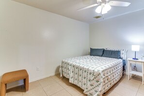 A bedroom with a bed, a nightstand, a lamp, a small wooden stool, and a ceiling fan. - Inviting Unit, 10 Mi to Airport & Vintage Park! (Houston)