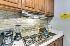 A kitchen with a gas stove, a blender, a sink, and wooden cabinets. - 10 Mi to Airport & Vintage Park! Quaint Apartment (Houston)