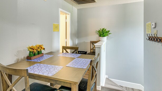 Un comedor con una mesa de madera, sillas y una planta en maceta.