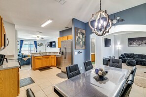 A modern kitchen with a central island, stainless steel appliances, and a dining area with a large table and chairs. - Swim, Golf & Park-hop! Family Home in Davenport (Davenport)