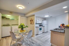 A modern kitchen with white appliances, a dining area with a glass table and chairs, and a small island with a sink. - Walk to Shops & Eats! Cape Coral Extended Escape (Cape Coral)
