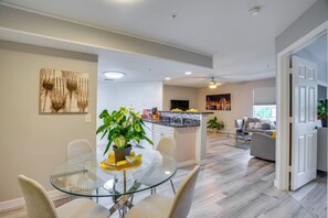 A modern kitchen with a central island, a dining area with a glass table, and a living space with a sofa. - Walk to Shops & Eats! Cape Coral Extended Escape (Cape Coral)