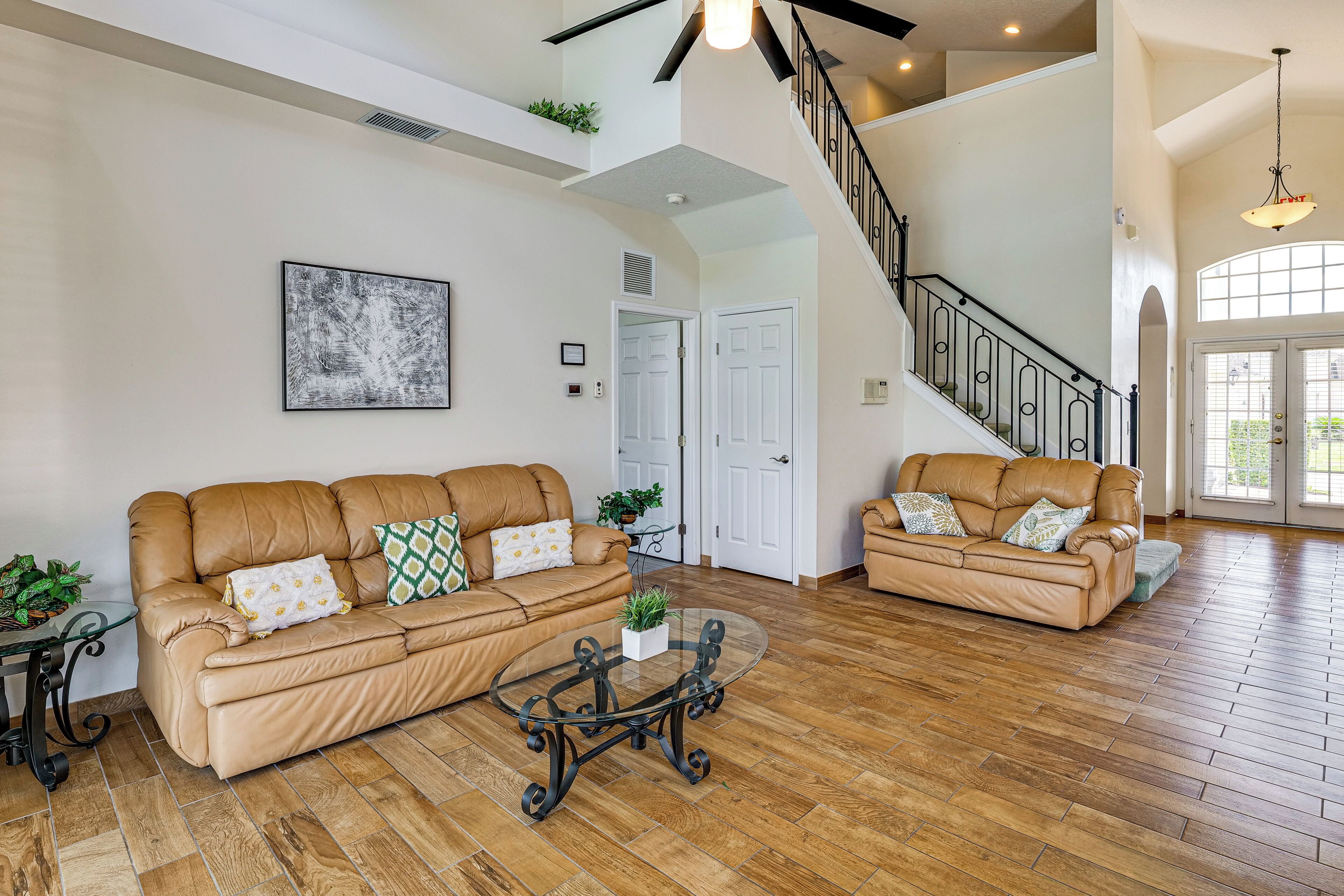 A spacious living room with two leather sofas, a glass coffee table, and a staircase leading to an upper level.
