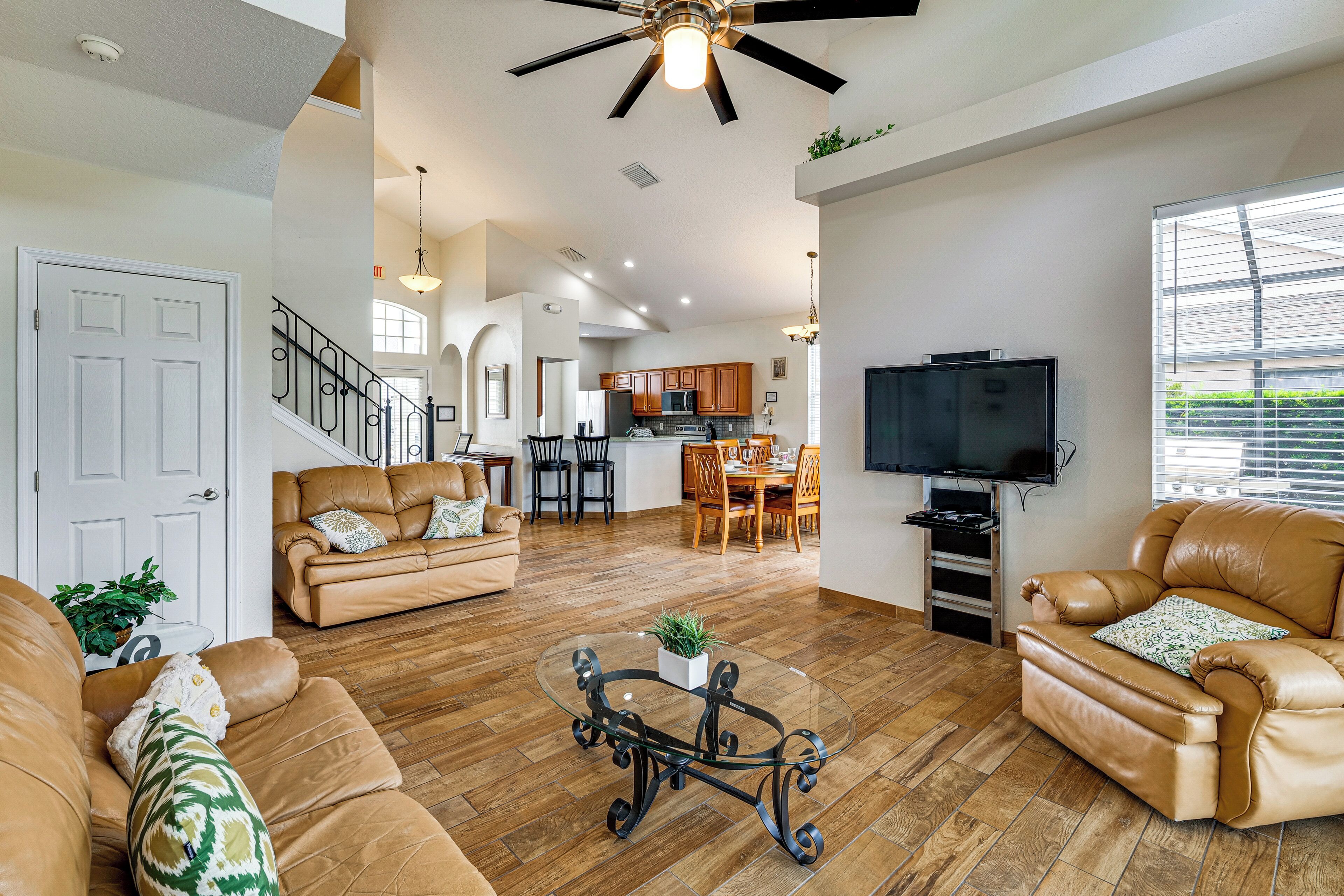 A spacious living room with leather sofas, a glass coffee table, and a television.