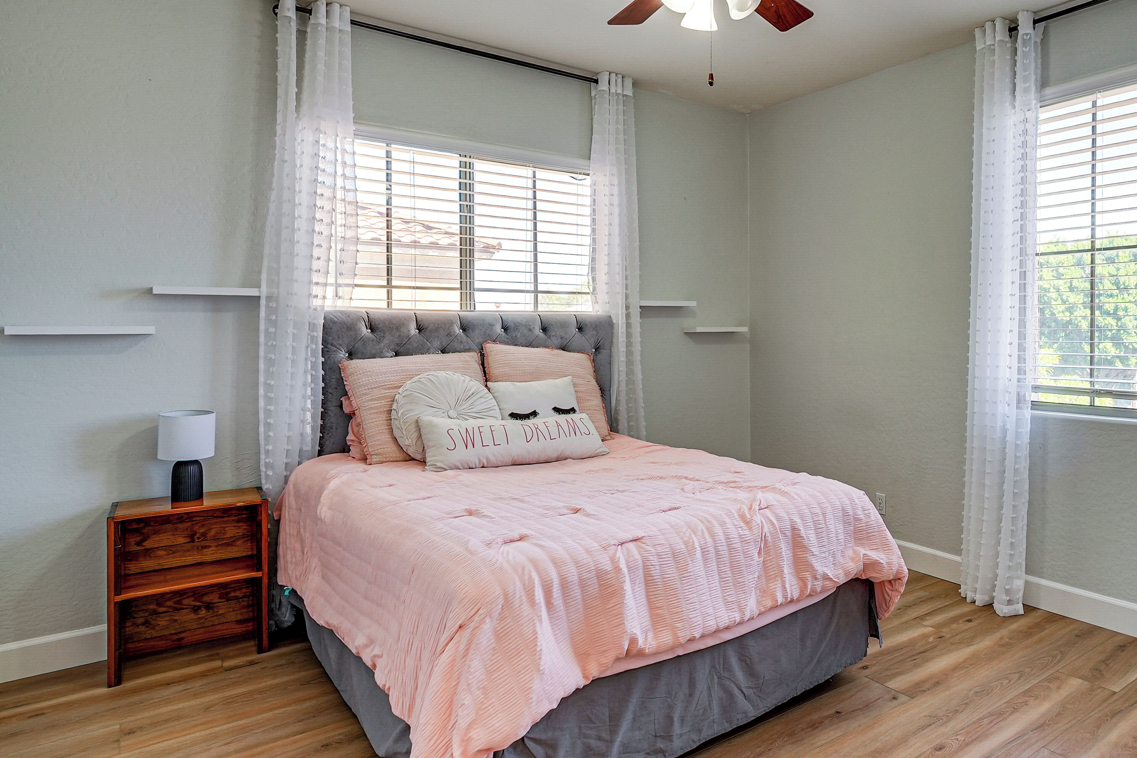 A bedroom with a bed, nightstand, and a ceiling fan.