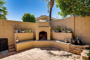 An outdoor patio with a built-in fire pit, surrounded by potted plants and a brick wall. - Outdoor Oasis w/ Pool! Glendale Group Escape (Glendale)