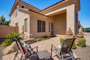 Una casa de dos pisos con un patio que tiene dos sillas y una mesa.