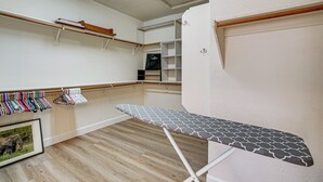 Huoneessa on puulattia, valkoinen seinä ja puinen hylly, jonka päällä on muutamia esineitä.