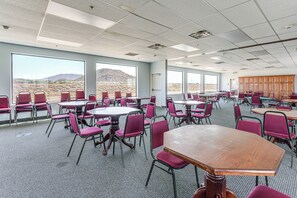 A conference room with tables and chairs, large windows with a desert view, and a carpeted floor. - Complimentary Golf Cart! Viewpoint Resort Home (Mesa)