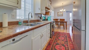 A kitchen with white cabinets, a stainless steel sink, a coffee maker, and a dining area with a table and chairs. - Complimentary Golf Cart! Viewpoint Resort Home (Mesa)