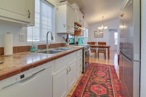 A kitchen with white cabinets, a stainless steel sink, a coffee maker, and a dining area with a table and chairs. - Complimentary Golf Cart! Viewpoint Resort Home (Mesa)