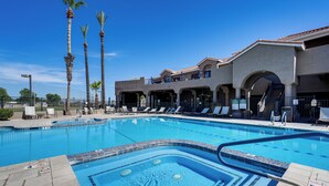 A swimming pool with lounge chairs, palm trees, and a building with arches and balconies. - Complimentary Golf Cart! Viewpoint Resort Home (Mesa)
