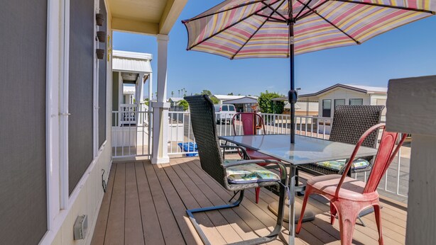 A covered outdoor patio with a table and chairs, a striped umbrella, and a view of the surrounding area. - Complimentary Golf Cart! Viewpoint Resort Home (Mesa)