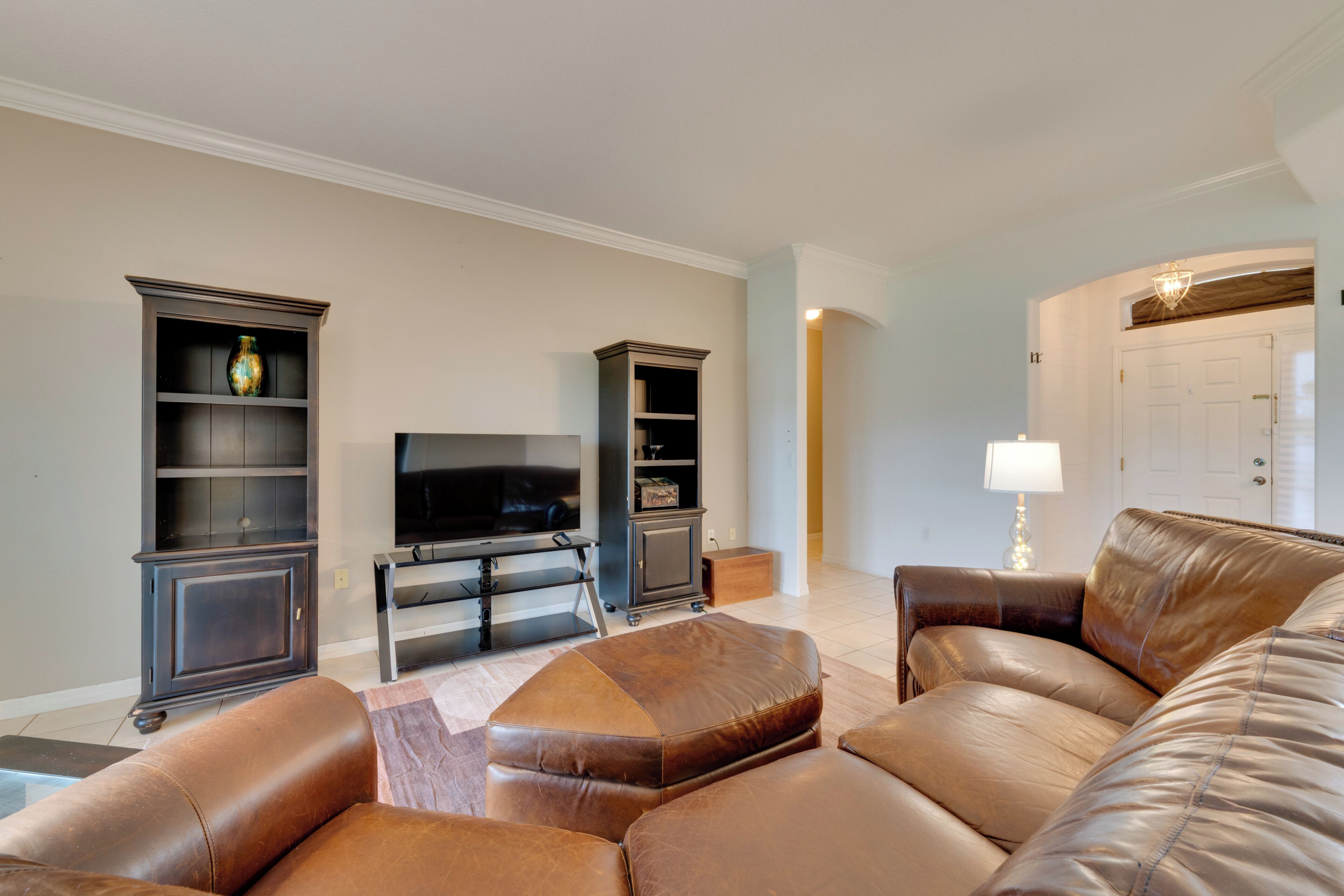 A living room with leather sofas, a flat-screen TV, and built-in shelving units.