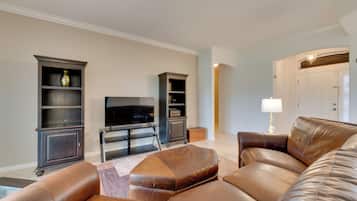 A living room with leather sofas, a flat-screen TV, and built-in shelving units.