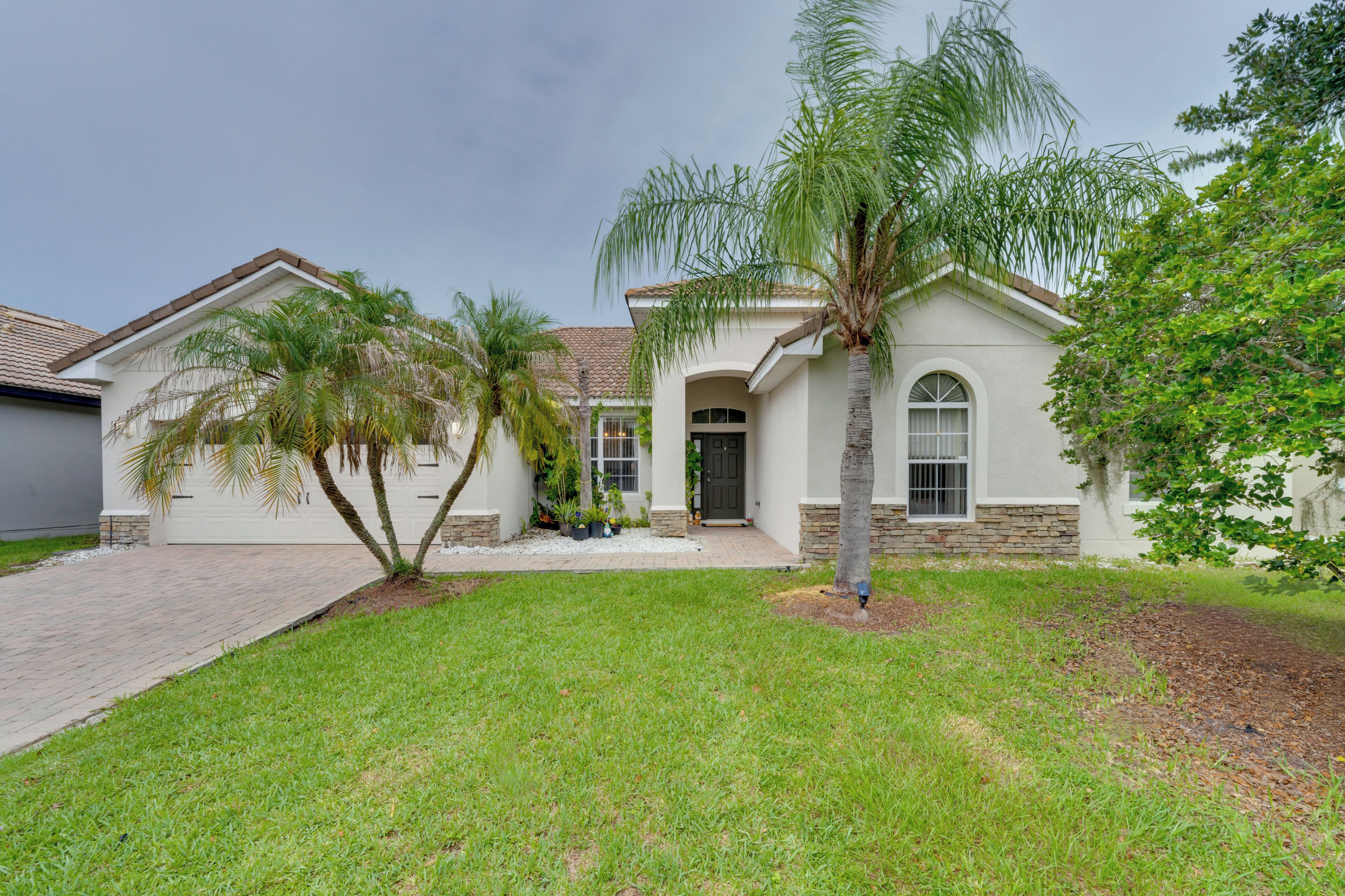A residential house with a front yard, a palm tree, and a driveway.