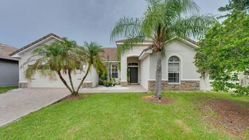 A residential house with a front yard, a palm tree, and a driveway.