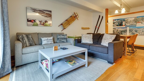 A modern living room with a grey sofa, a white coffee table, and a wooden dining table with chairs. - Hike, Bike & Ski! Cozy Condo 8 Mi to Lake Dillon (Breckenridge)
