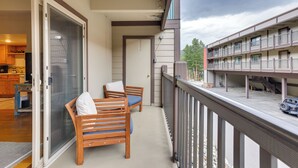 A balcony with two wooden chairs and a table, overlooking a parking area and a building with multiple balconies. - Hike, Bike & Ski! Cozy Condo 8 Mi to Lake Dillon (Breckenridge)