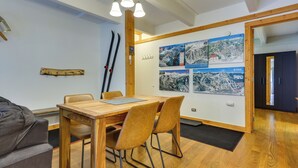 A dining area with a wooden table and chairs, a ski rack, and wall-mounted ski maps. - Hike, Bike & Ski! Cozy Condo 8 Mi to Lake Dillon (Breckenridge)