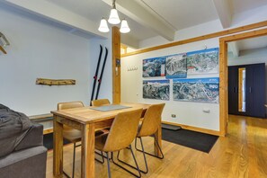 A dining area with a wooden table and chairs, a ski rack, and wall-mounted ski maps. - Hike, Bike & Ski! Cozy Condo 8 Mi to Lake Dillon (Breckenridge)