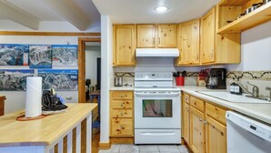 A kitchen with wooden cabinets, a white stove, and a tiled backsplash. - Hike, Bike & Ski! Cozy Condo 8 Mi to Lake Dillon (Breckenridge)