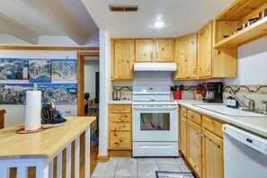 A kitchen with wooden cabinets, a white stove, and a tiled backsplash. - Hike, Bike & Ski! Cozy Condo 8 Mi to Lake Dillon (Breckenridge)