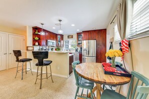 A kitchen with a central island, bar stools, a dining table, and a refrigerator. - Walk to Park & Pool: Sarasota Family Home w/ Yard (Sarasota)