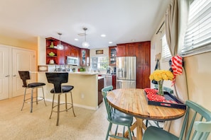 A kitchen with a central island, bar stools, a dining table, and a refrigerator. - Walk to Park & Pool: Sarasota Family Home w/ Yard (Sarasota)