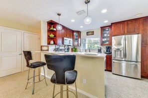 A kitchen with wooden cabinets, stainless steel appliances, a bar stool, and pendant lighting. - Walk to Park & Pool: Sarasota Family Home w/ Yard (Sarasota)