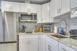 A modern kitchen with white cabinets, stainless steel appliances, and a marble countertop. - Work & Relax in Safety Harbor! Modern Coastal Apt (Safety Harbor)