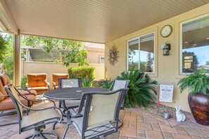 Un espace extérieur aménagé en terrasse, avec une table et des chaises, une horloge et un panneau d’accueil.