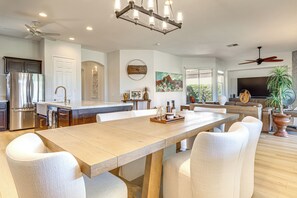 A spacious kitchen with a central island, modern appliances, and a dining area with a long table and chairs. - Indian Palms Retreat Across From Empire Polo Club (Indio)