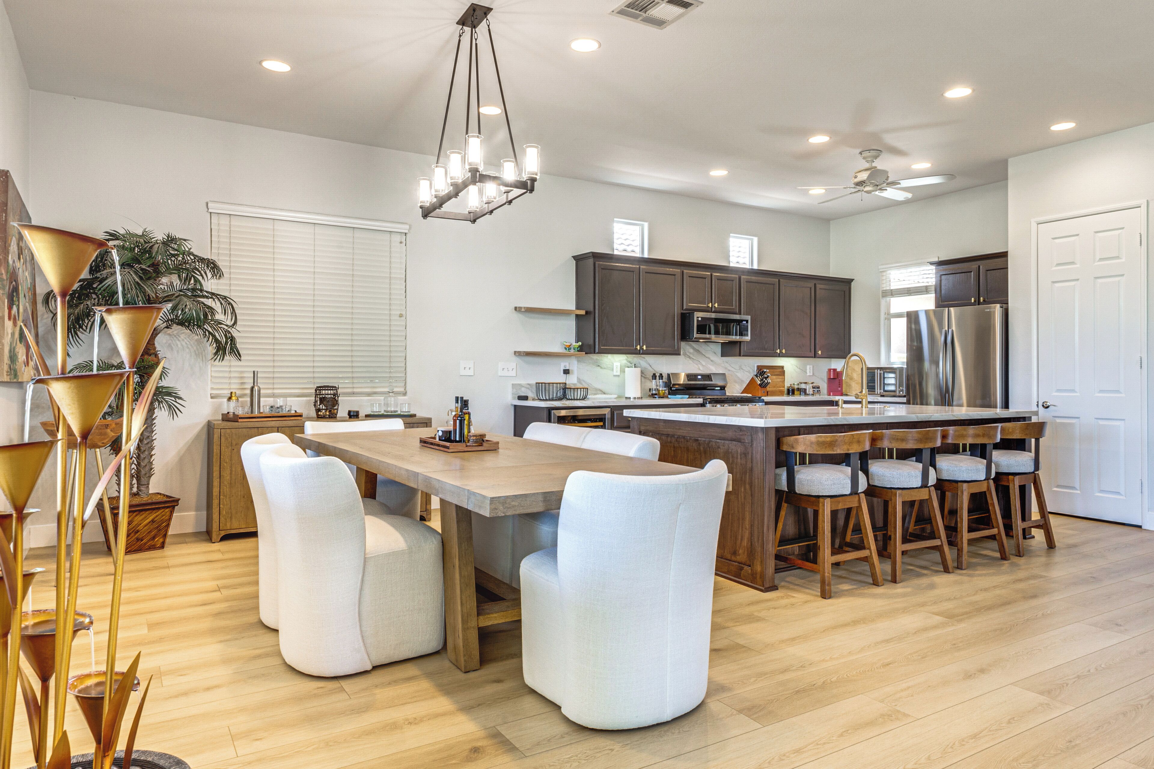 Cozinha moderna com ilha central, banquetas e mesa de jantar.